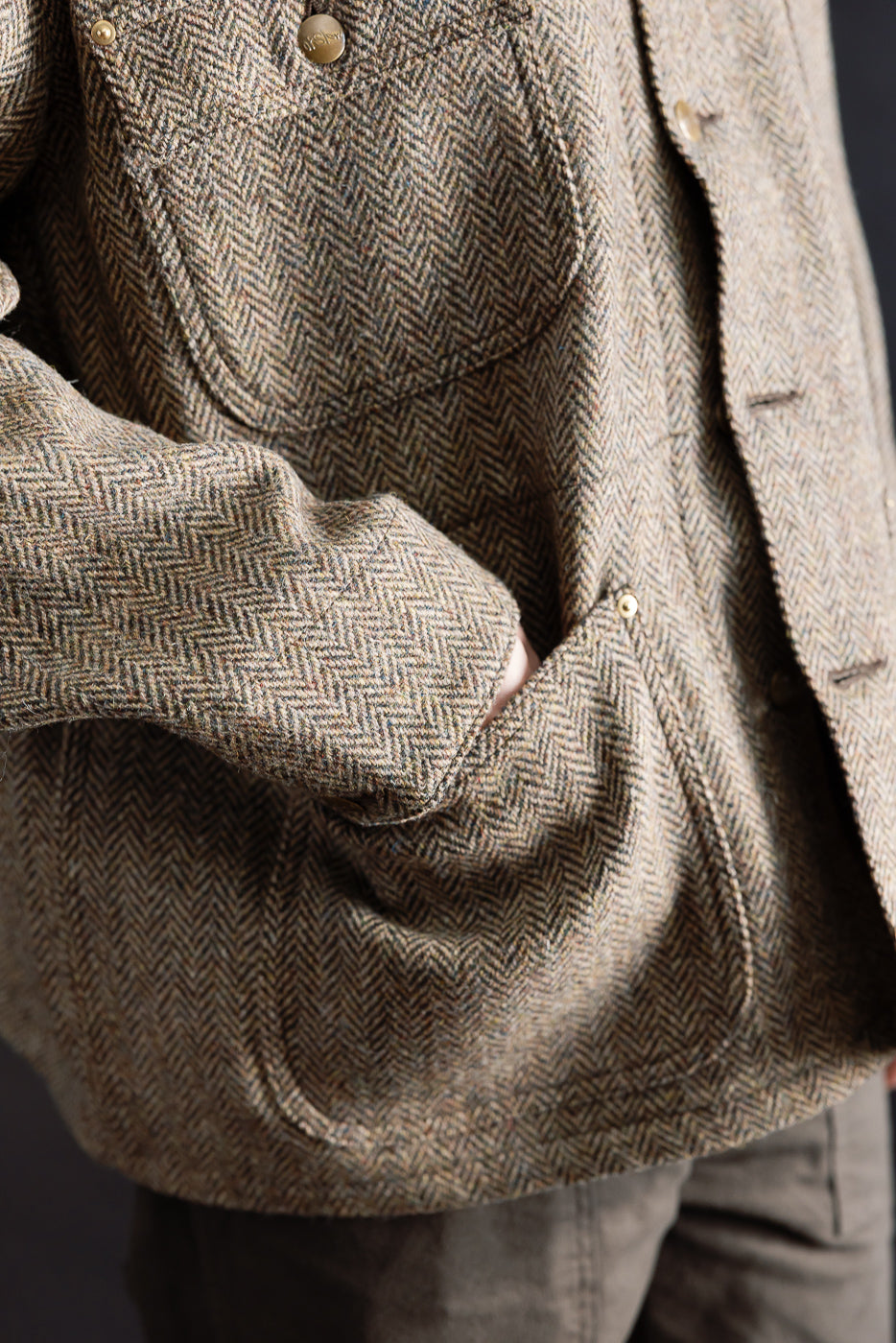 Close-up of orSlow Harris Tweed relaxed fit coverall jacket front pocket, button, and herringbone texture on male model, Dant shop.