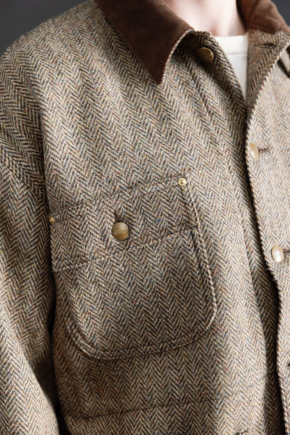 Close-up of front chest pocket and brown collar on Harris Tweed coverall jacket, worn by male model 5'9