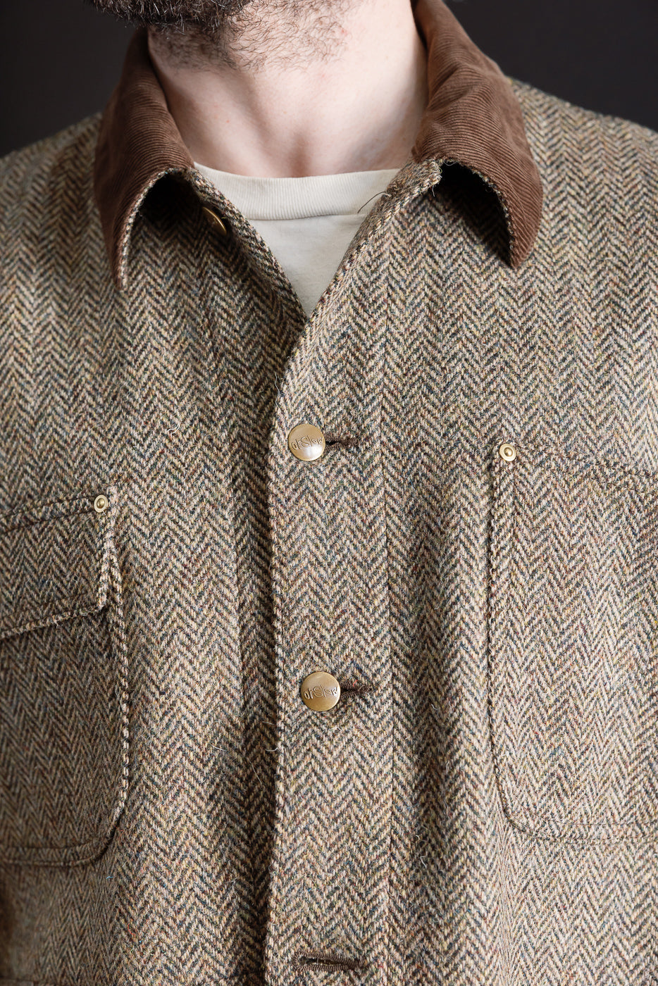 Close-up front of Orslow Harris Tweed coverall jacket, brown corduroy collar, herringbone wool, metal buttons, on male model 5'9
