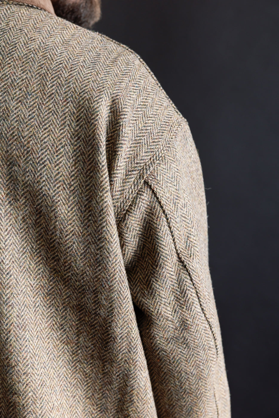 Close-up of Harris Tweed khaki relaxed fit coverall jacket shoulder seam, herringbone texture, male model, back left side view