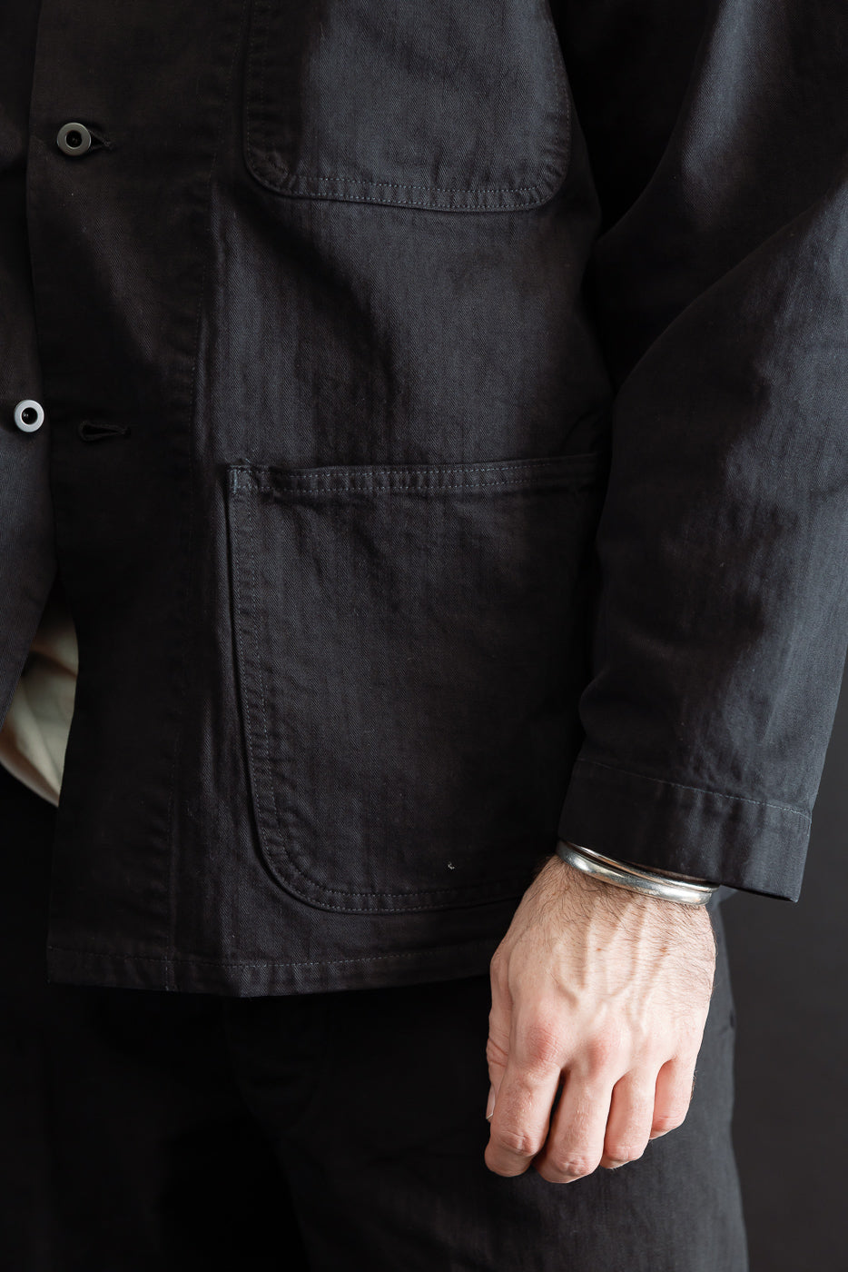 Close-up of the front left side of a black jacket on a male model, 5'9