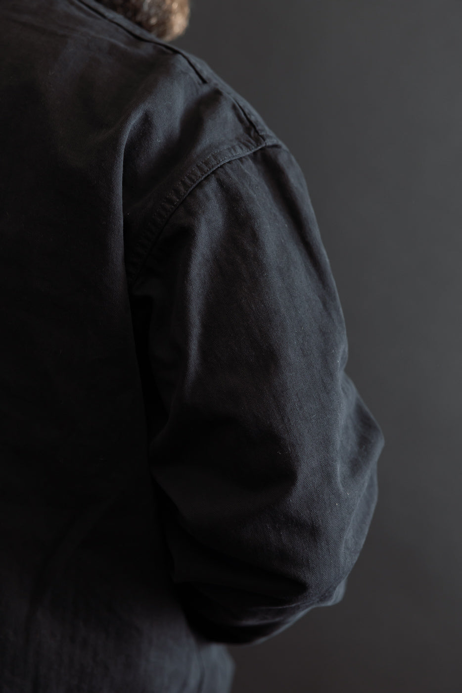 Close-up of the back view of a black cotton shirt sleeve showing fabric texture.
