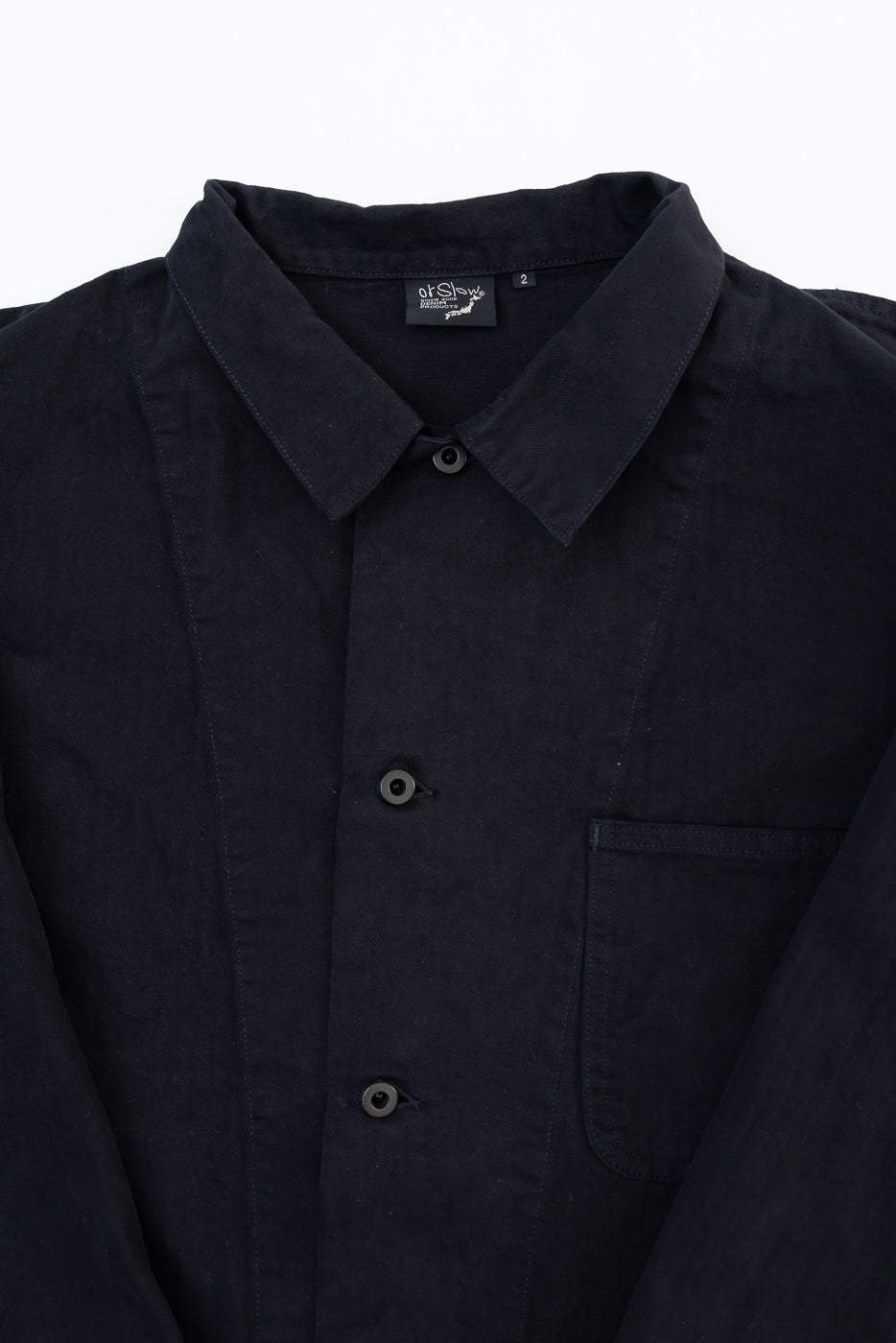 Close-up front view of a black shirt featuring a collar, buttons, pocket, and inner tag.