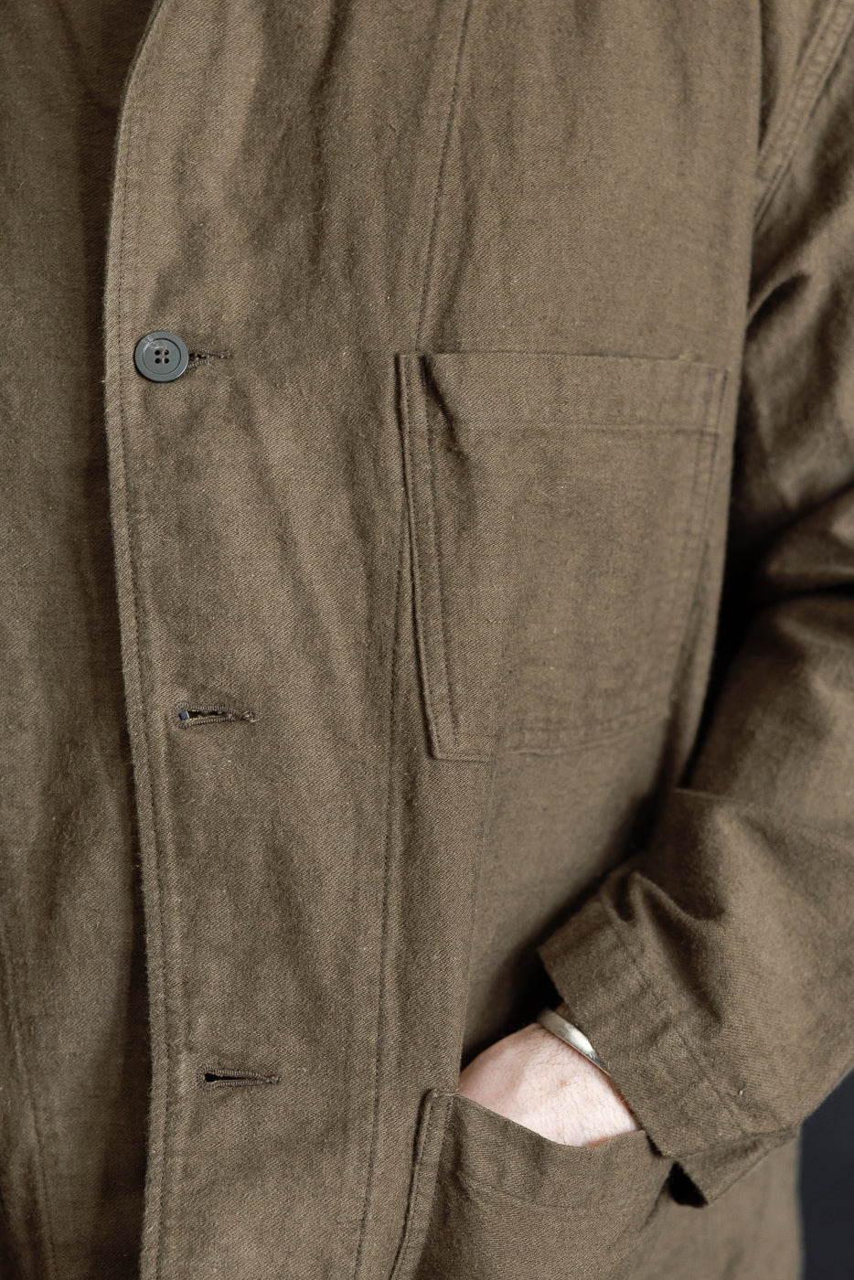 Close-up front of brown moleskin work jacket, left chest pocket, button, textured fabric