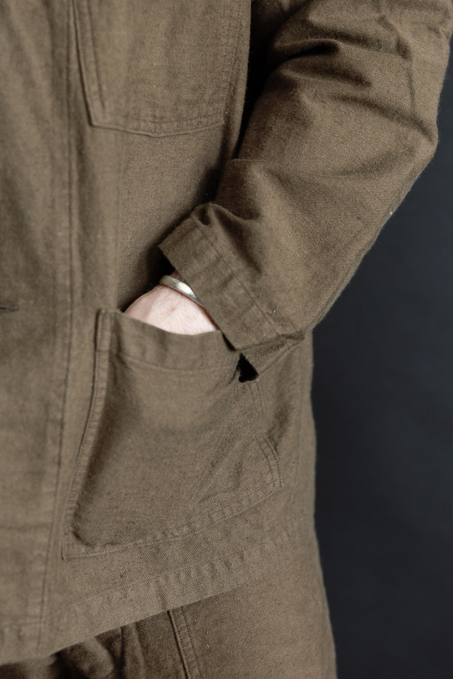 Close-up front pocket of orSlow coffee brown moleskin work jacket on male model, sleeve detail visible