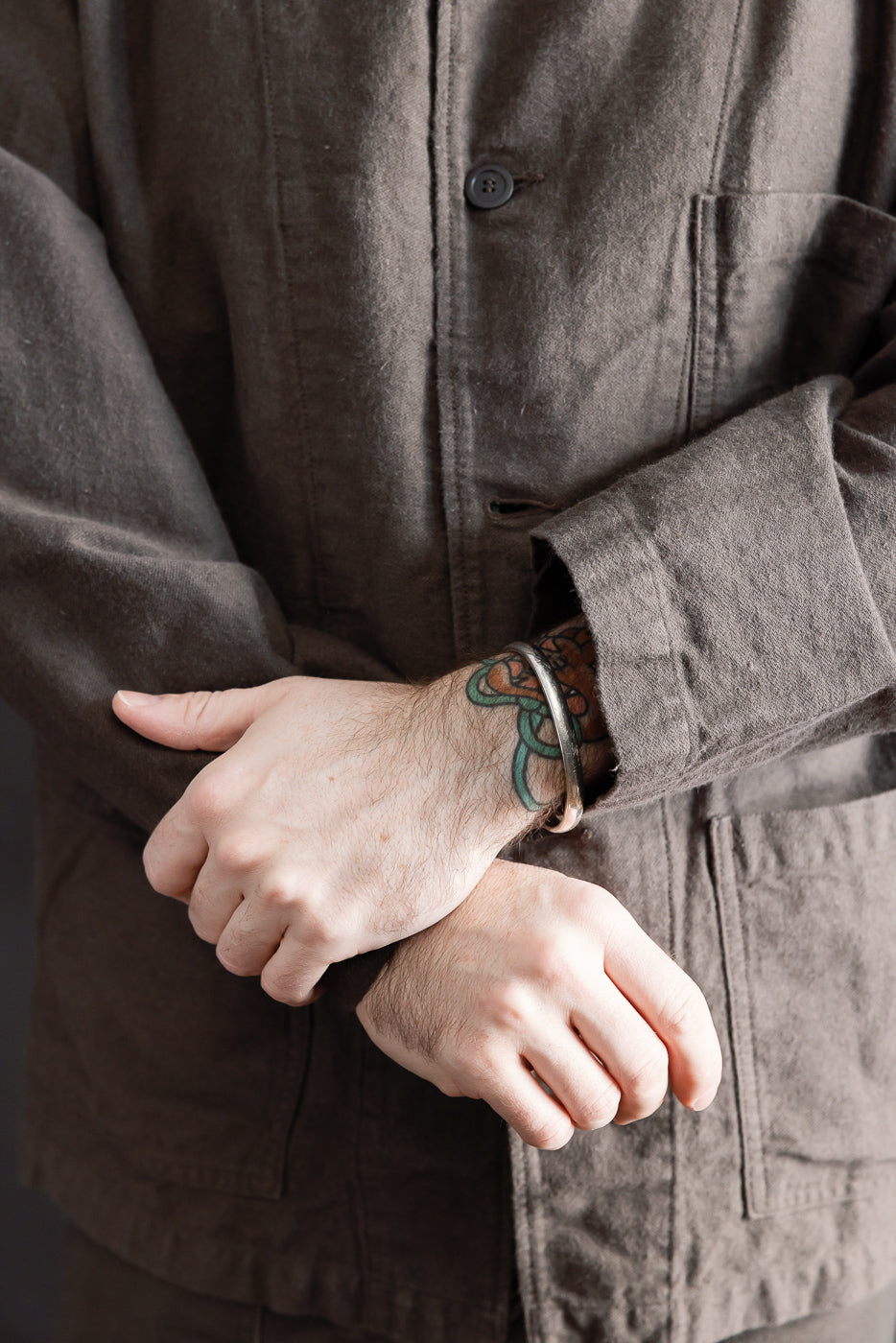 Close-up front detail of orSlow charcoal moleskin work jacket on male model, showing button, fabric texture, and patch pockets. Model is 5'9