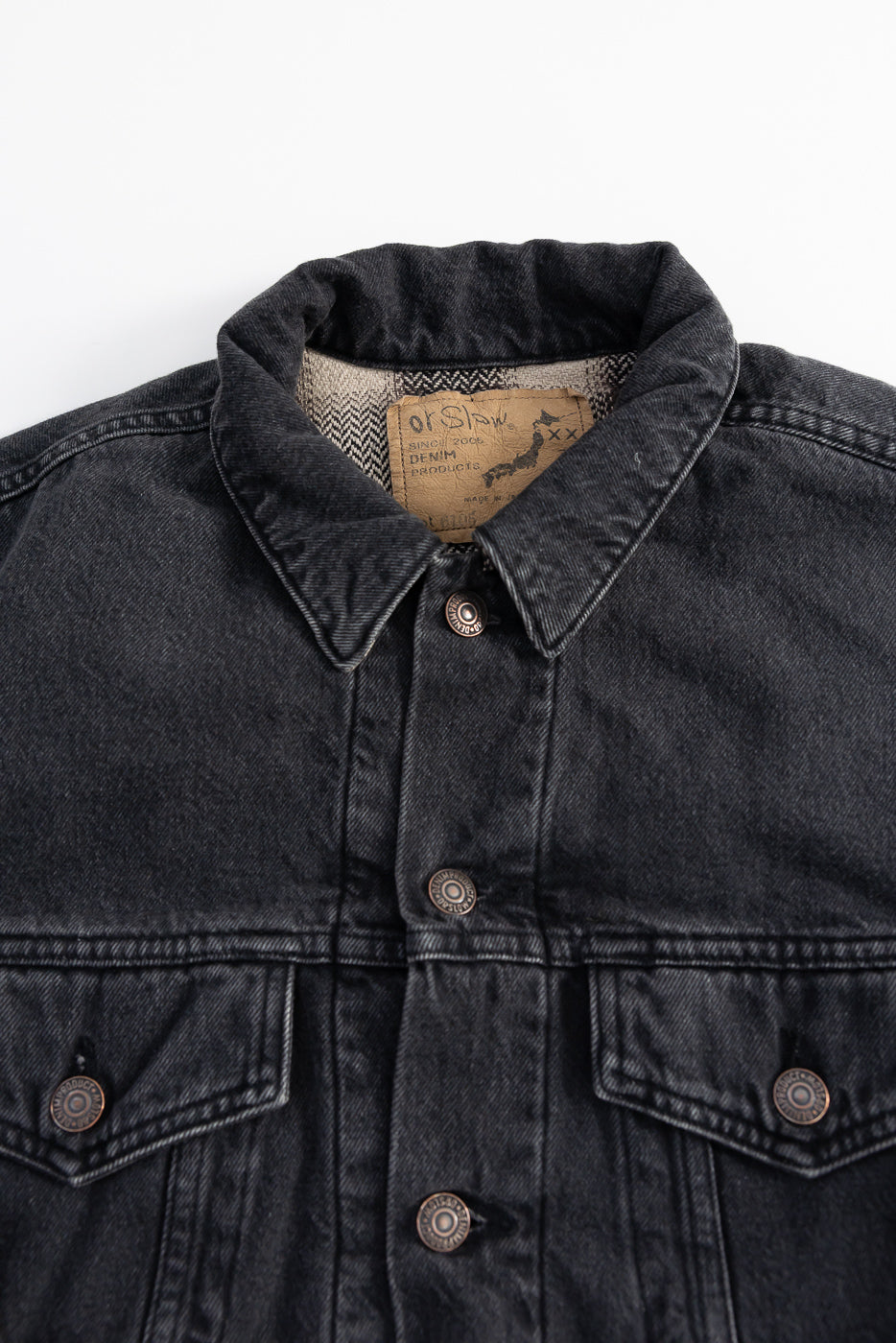Close-up front of orSlow black denim Type 3 jacket, metal buttons, collar, and inner label detail