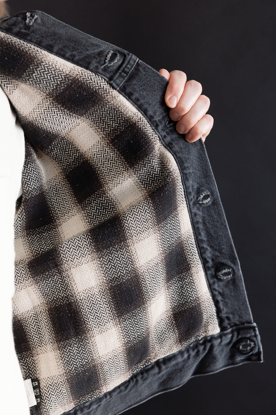 Close-up of orSlow Type 3 denim jacket, black stone wash, showing plaid flannel check lining detail.