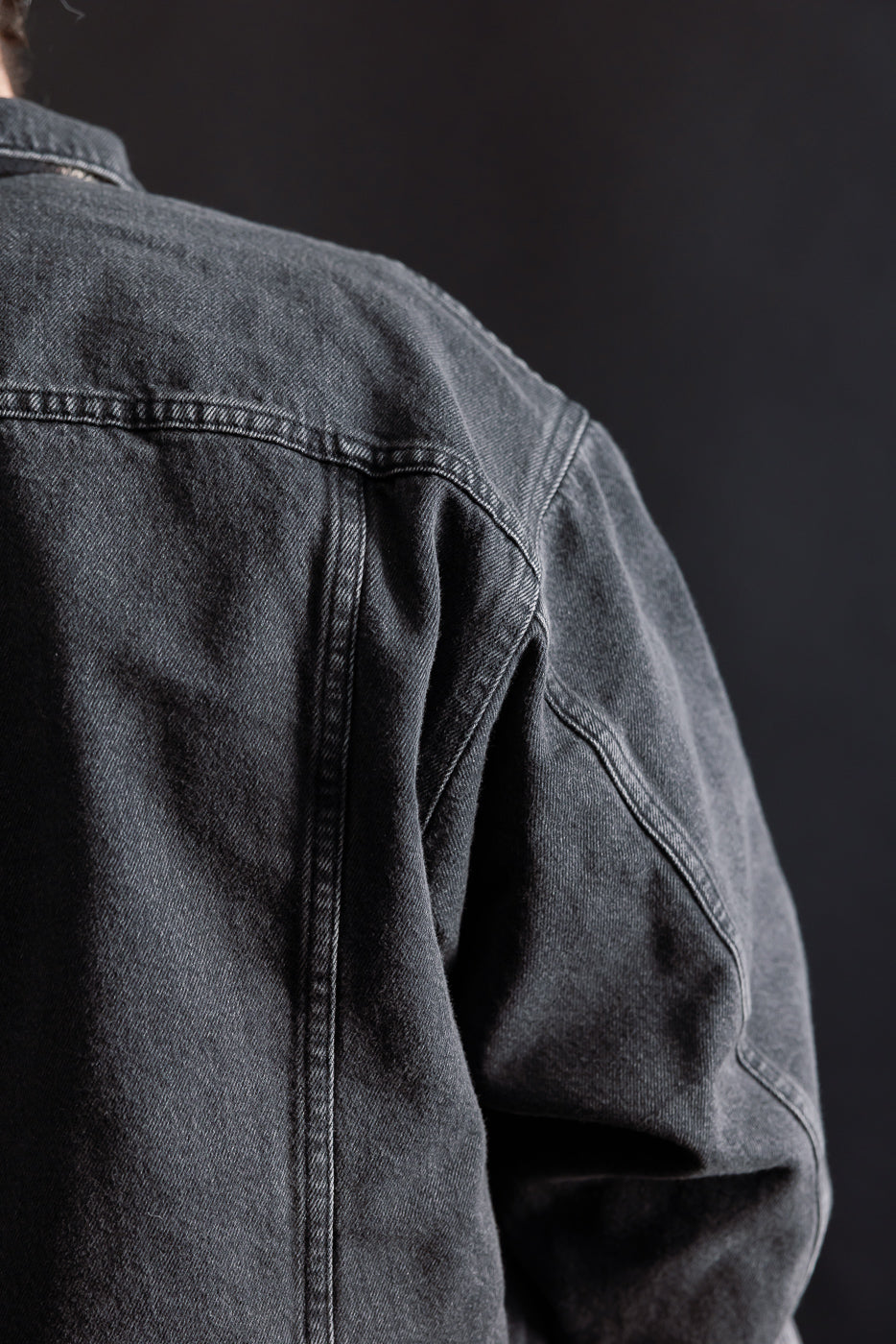 Close-up of back shoulder and seam detail on black organic cotton denim jacket