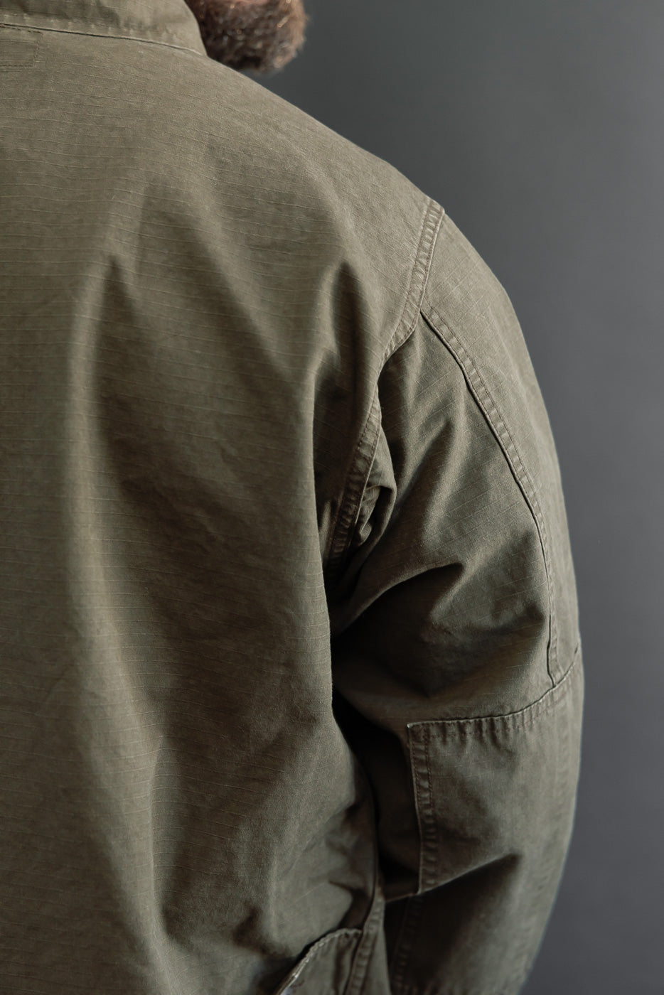 Close-up back and side view of an olive green jacket on a male model, 5'9