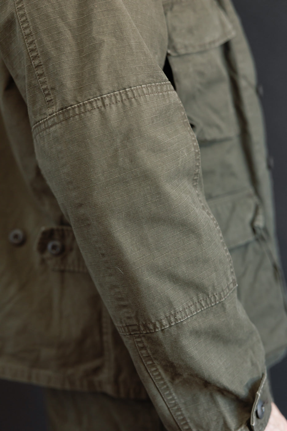 Close-up of the left sleeve of an olive green jacket on a male model, 5'9