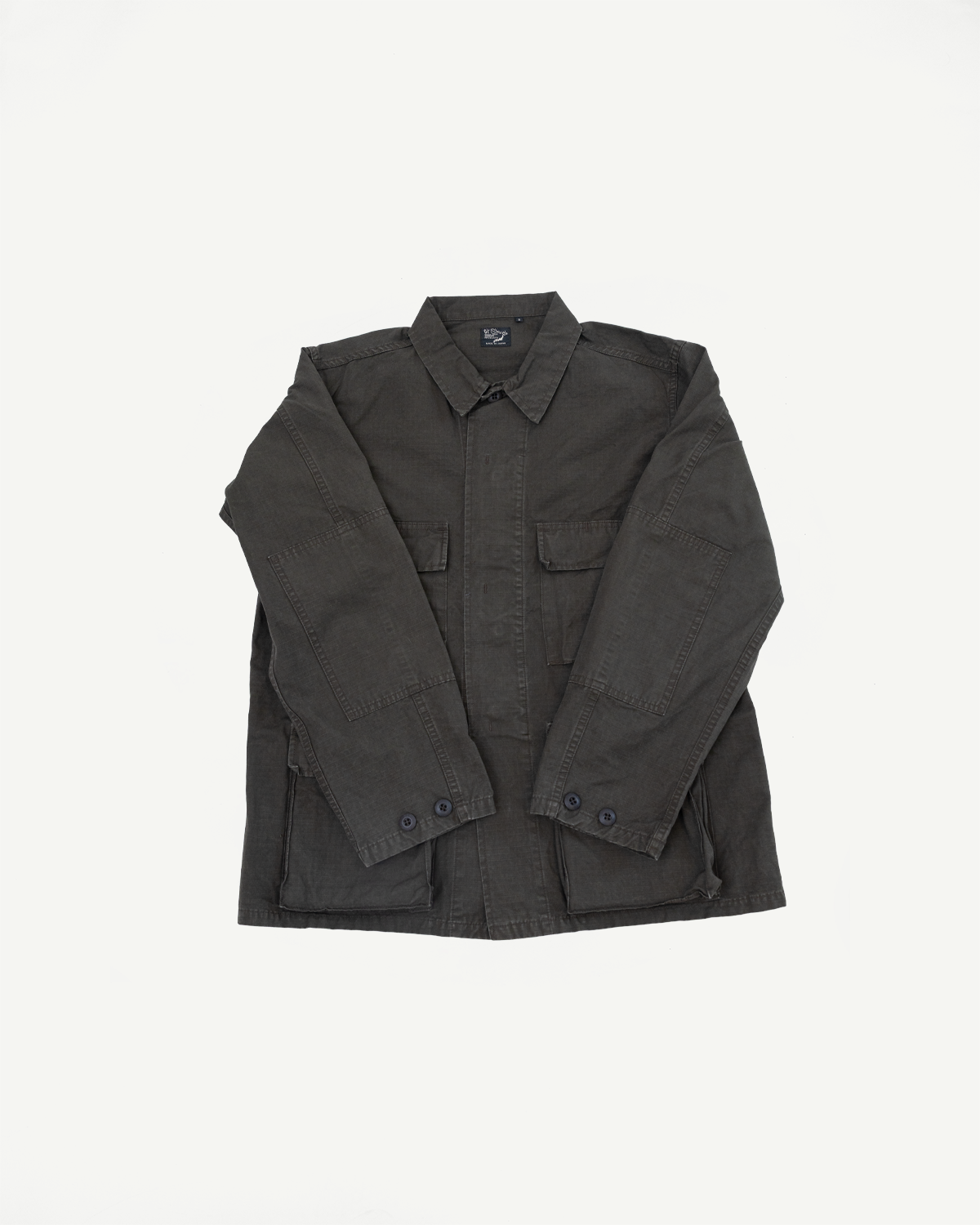 Front view flat lay of a dark charcoal utility field jacket with chest and hip pockets.