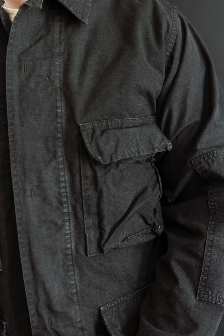 Close-up of the 01-6110-61S Ripstop BDU Jacket in Black Stone, highlighting its military-style design with a front button placket and multiple flap pockets, crafted from textured Japanese ripstop fabric.