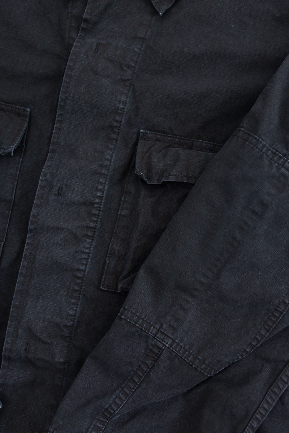 Close-up of the 01-6110-61S Ripstop BDU Jacket - Black Stone, highlighting the buttoned front placket, flap-style patch pockets, and reinforced sleeve stitching, showcasing orSlow's Japanese ripstop fabric and military-inspired design.