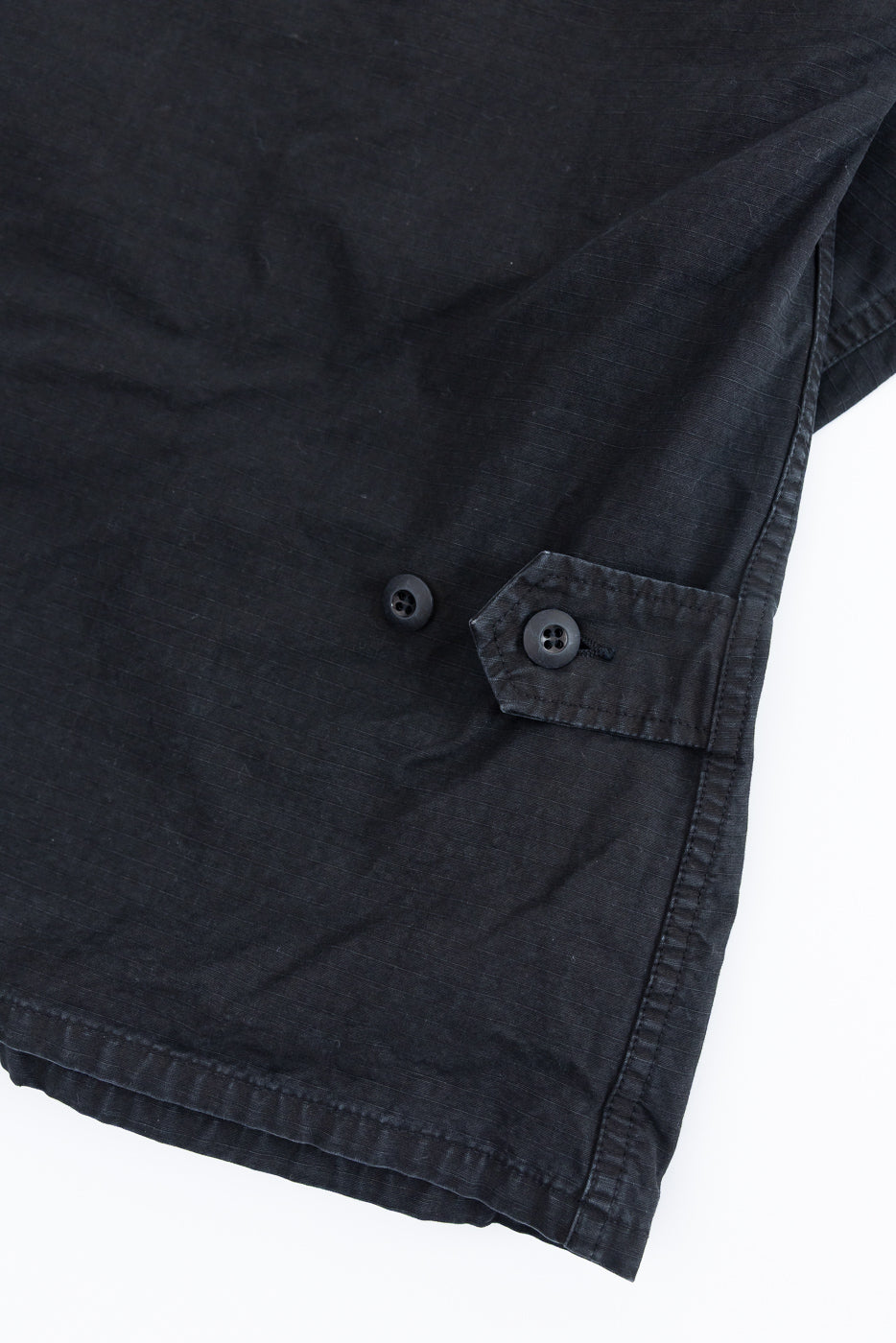 Close-up of the 01-6110-61S - Ripstop BDU Jacket - Black Stone, highlighting ripstop fabric, black four-hole buttons, and an adjustable tab detail on the hem, showcasing its military-inspired design.