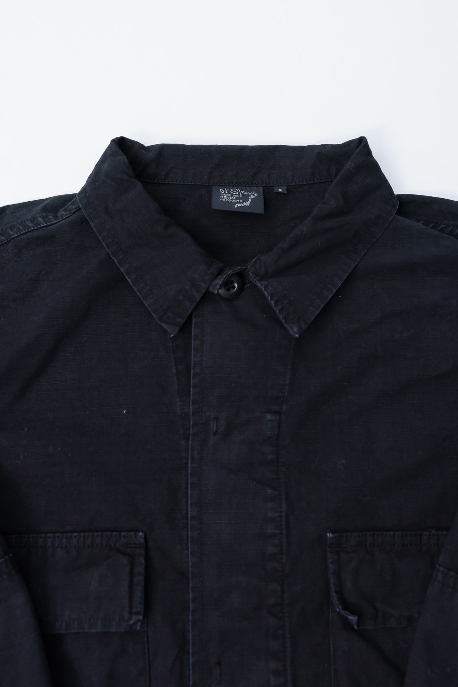 Close-up front view of orSlow black ripstop BDU jacket collar, button, and chest pockets