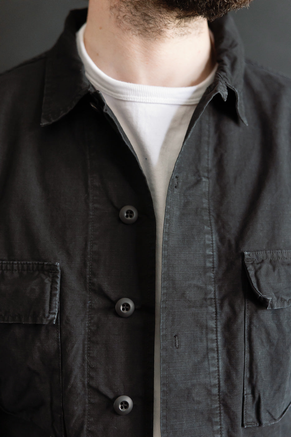 Close-up front view of Orslow black ripstop BDU jacket on male model, 5'9