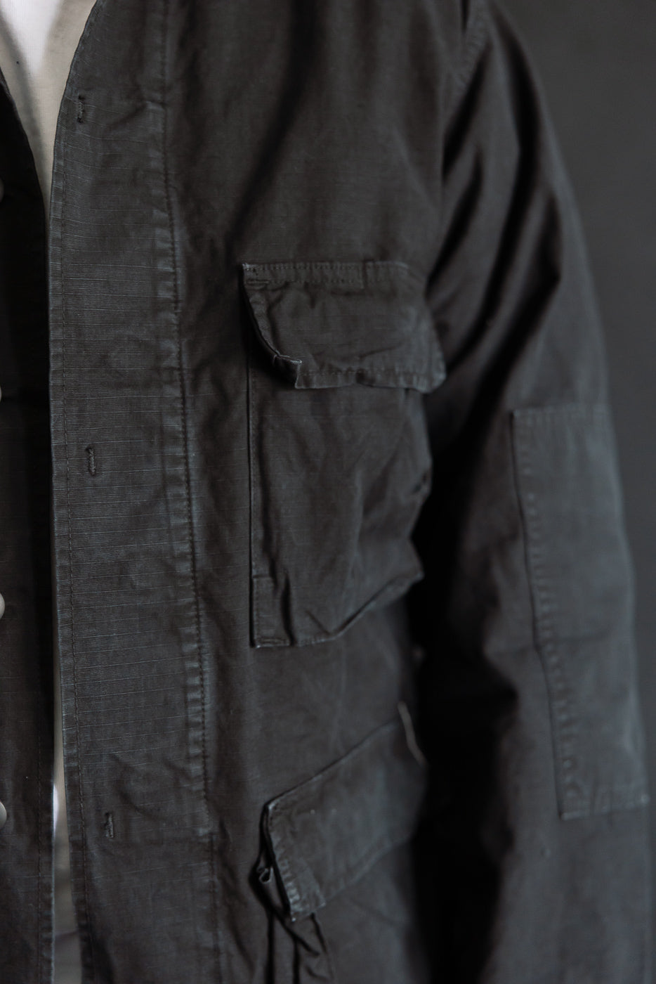 Close-up of front right side orSlow Ripstop BDU jacket in black, showing pockets, on male model, 5'9