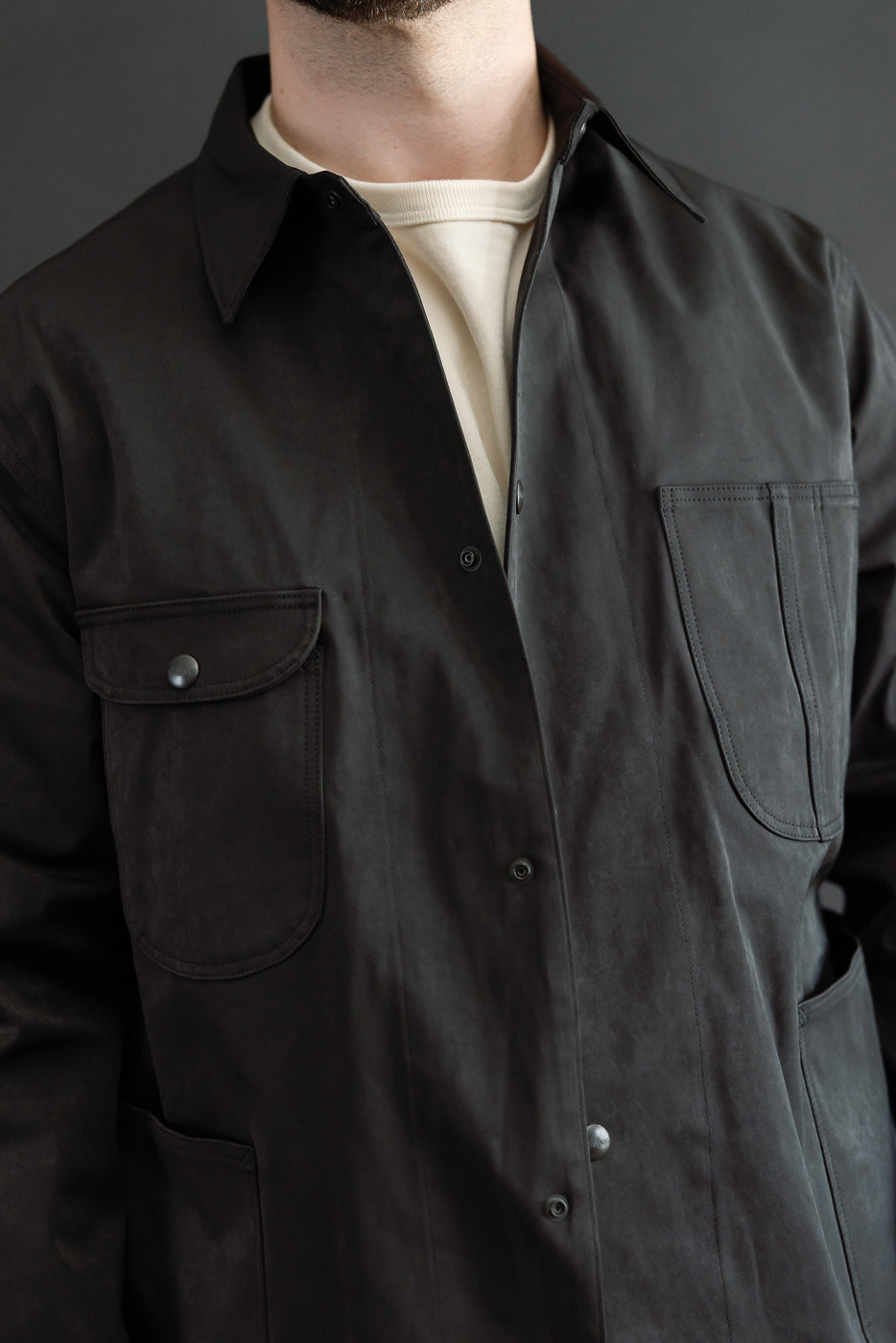 Close-up, front view of a male model wearing a dark brown button-down shirt with chest pockets.
