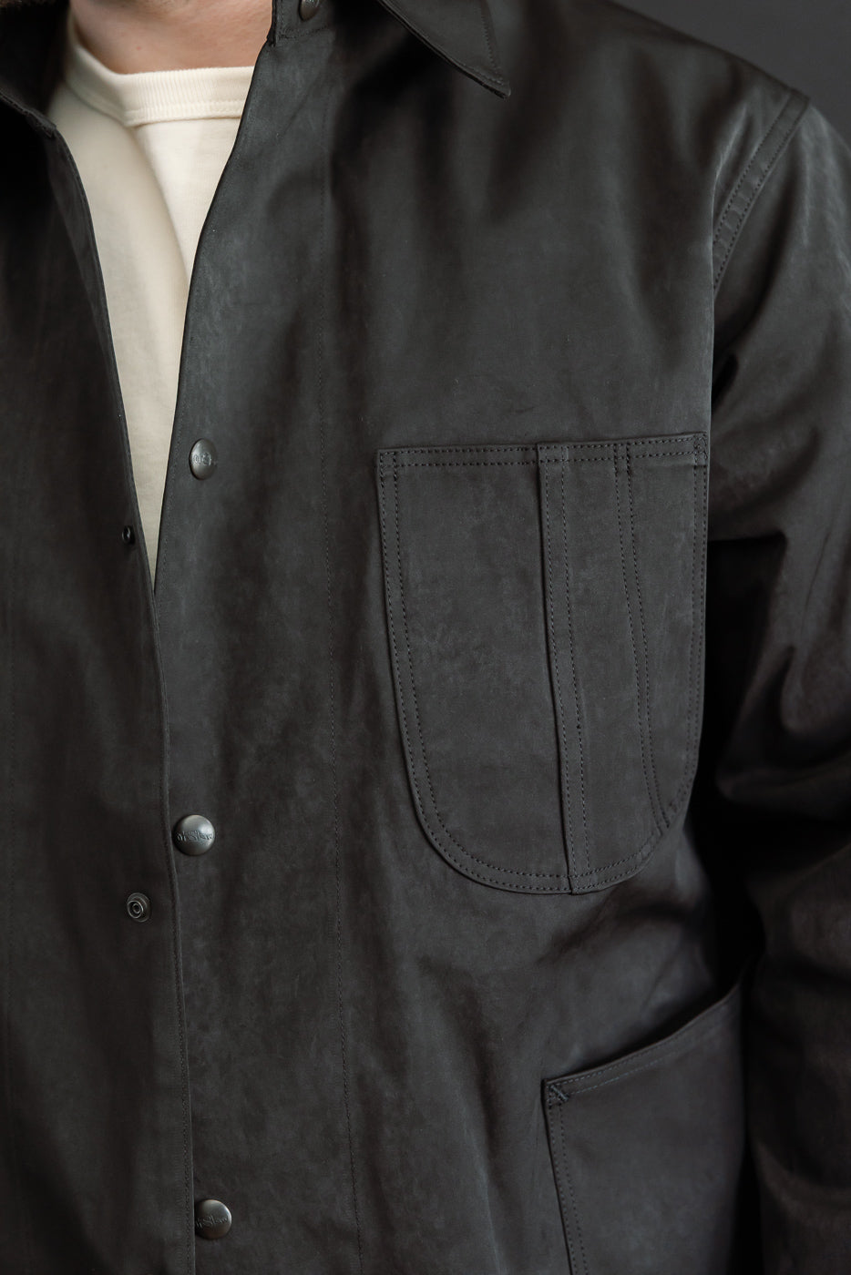 Close-up front view of a black casual jacket showing the chest pocket and button details.