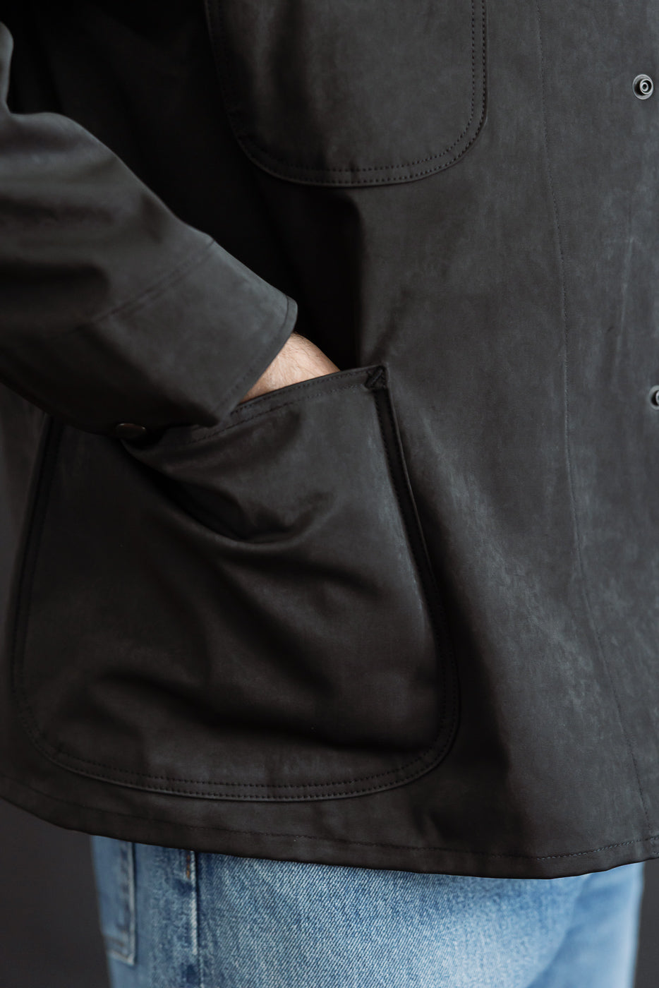 Close-up of the front side of a male model's black casual jacket, showing a large patch pocket.