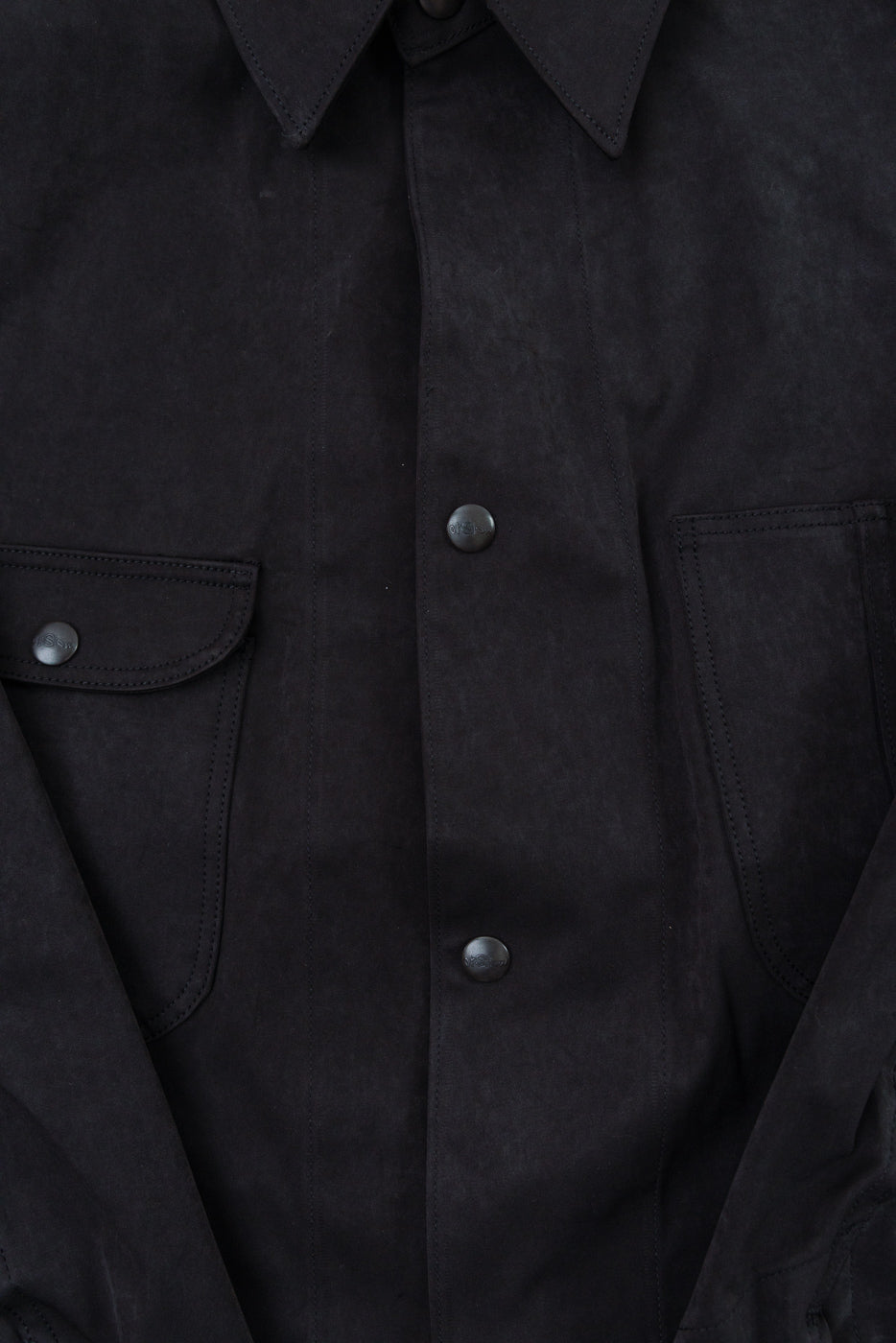 Close-up front view of a black textured button-down shirt showing snap buttons and chest pocket.