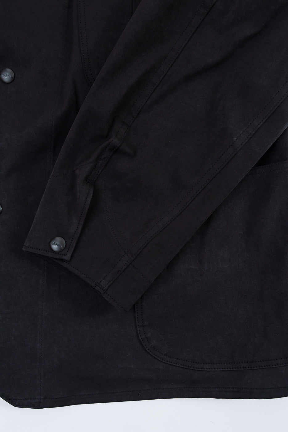 Close-up of a black jacket sleeve and front, showing fabric texture and a button cuff.