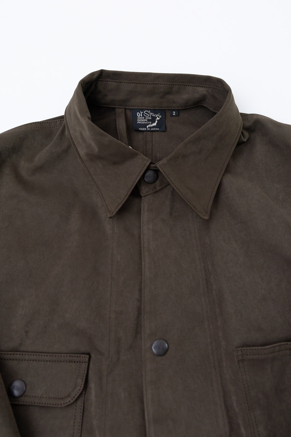 Front view close-up of a dark olive suede jacket showing the collar and button details.