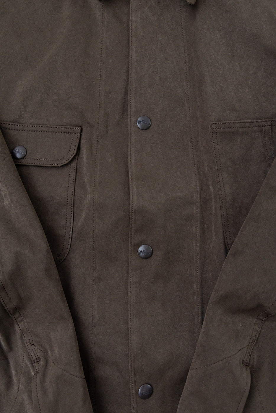 Close-up front view of a brown waxed canvas jacket showing button details and fabric texture.
