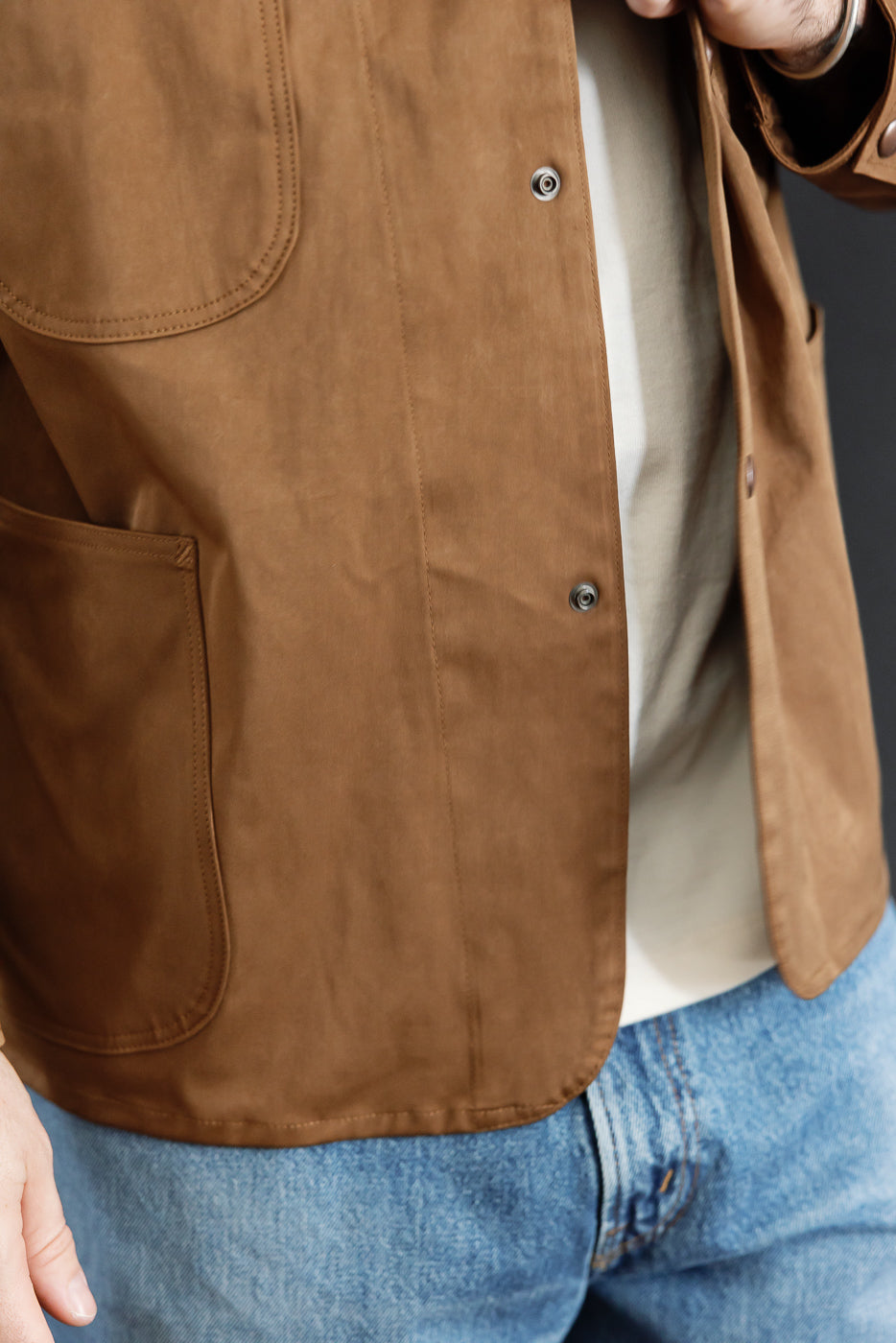 Close-up of the front right side of a brown jacket on a male model, 5'9