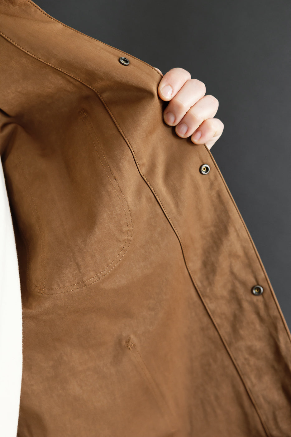 Close-up of the front side of a brown cotton button-down shirt showing fabric texture and buttons.