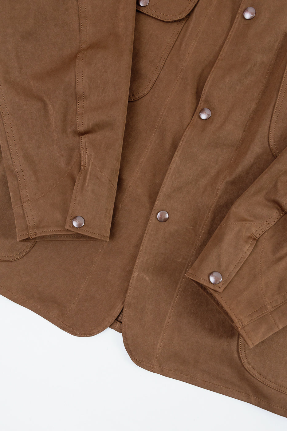 Close-up front view of a brown cotton utility jacket showing buttons and sleeve details.