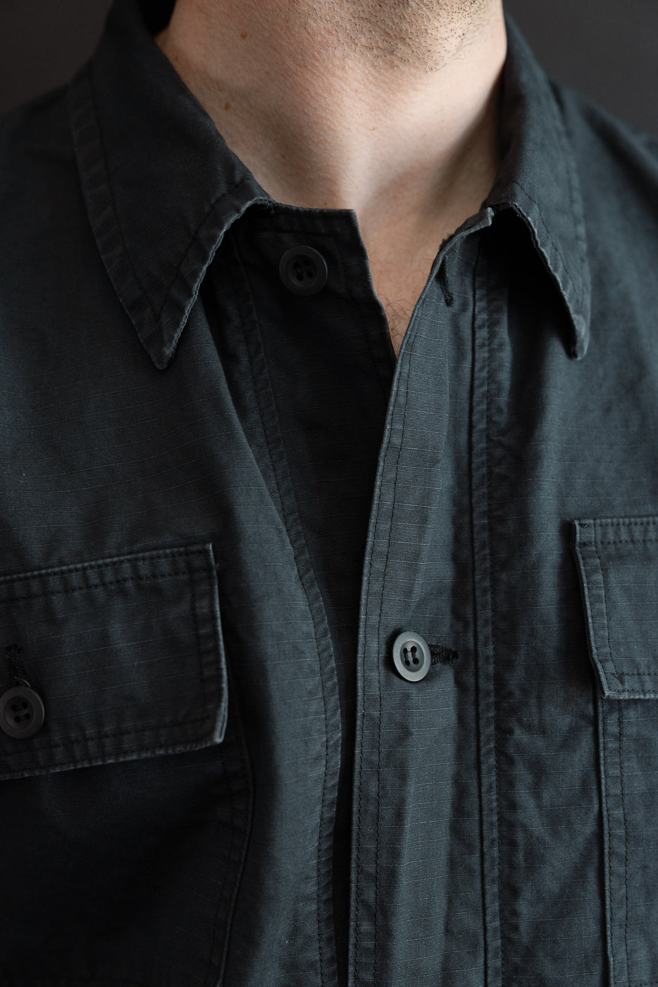 Close-up front view of dark gray button-up shirt on male model, 5'9