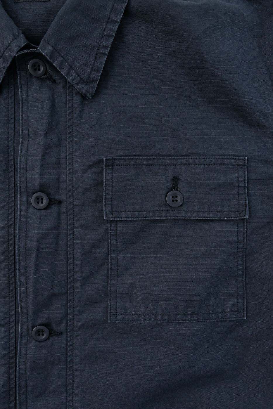 Close-up front view of dark shirt with buttoned chest pocket, collar, and fabric texture details