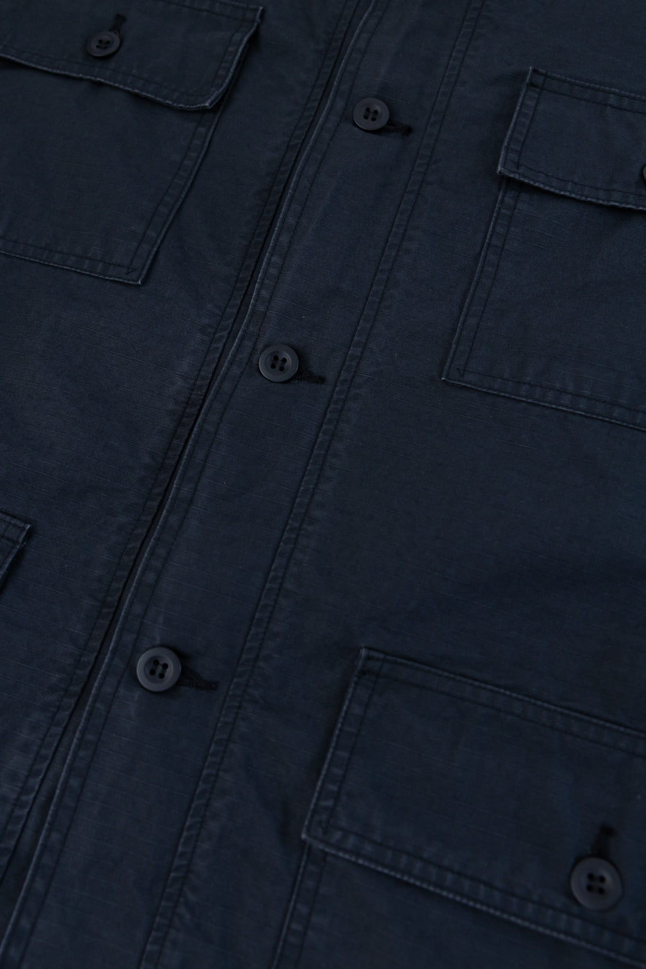 Close-up front view of dark navy shirt showing button placket, chest pockets, and fabric texture