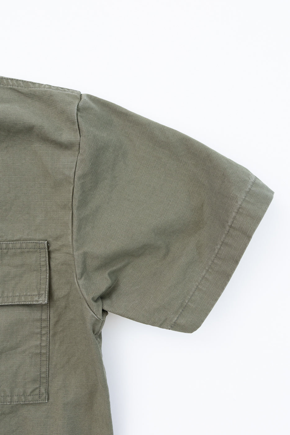 Close-up of the orSlow 01-8046-76k Utility Short Sleeve Work Shirt Jacket in army green, showcasing its ripstop fabric texture, right sleeve, and flap-closure patch pocket, reflecting utilitarian design.