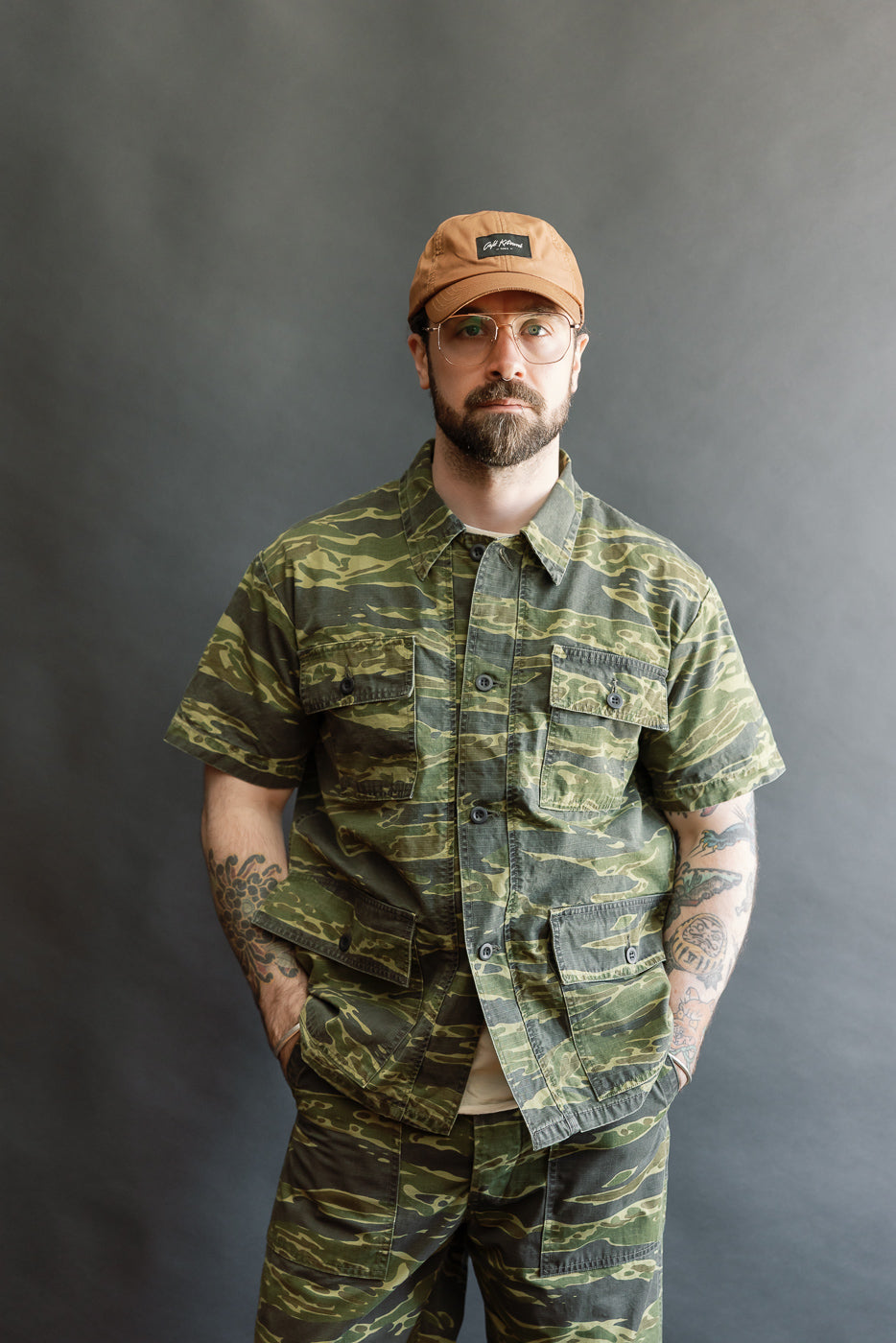 Man models the 01-8046 -TGC - Utility Short Sleeve Work Shirt Jacket in Tiger Camo, showcasing its relaxed fit, utility pockets, and distinctive camouflage pattern, embodying Dant's premium workwear aesthetic.