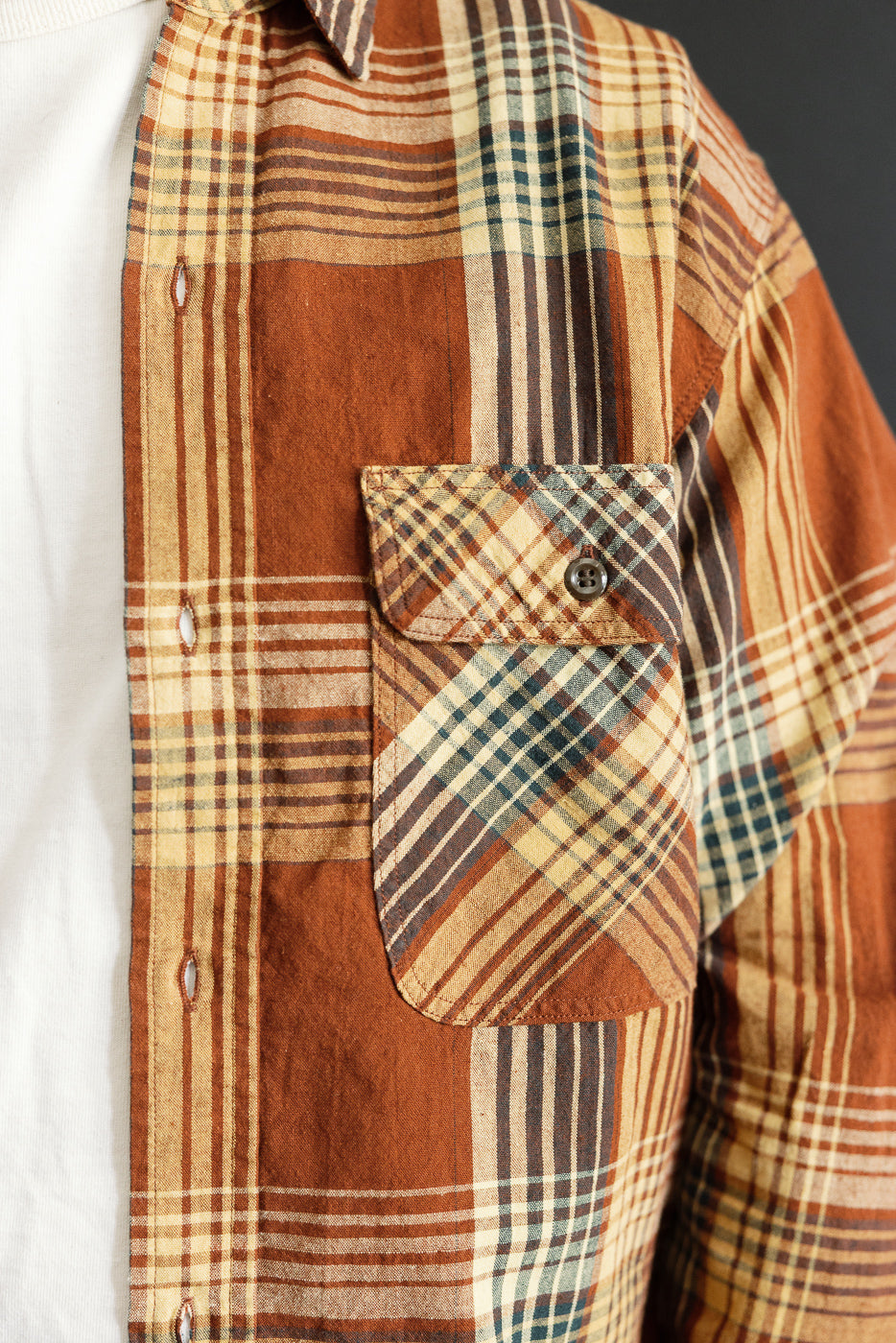 Close-up front view of men's plaid shirt, chest pocket with button, brown & tan pattern, athletic fit