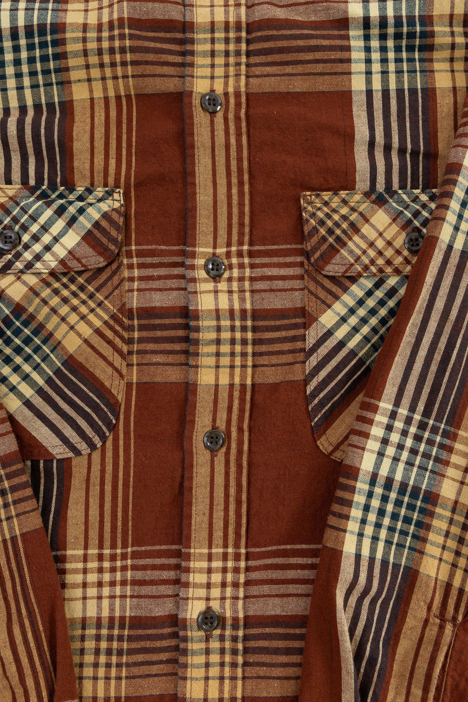 Close-up front view of men's plaid shirt with button details, chest pockets, and striped fabric texture