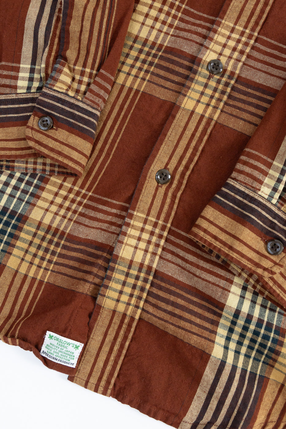 Close-up front view of patchwork plaid shirt with button details, fabric texture, and Orslow's tag on hem