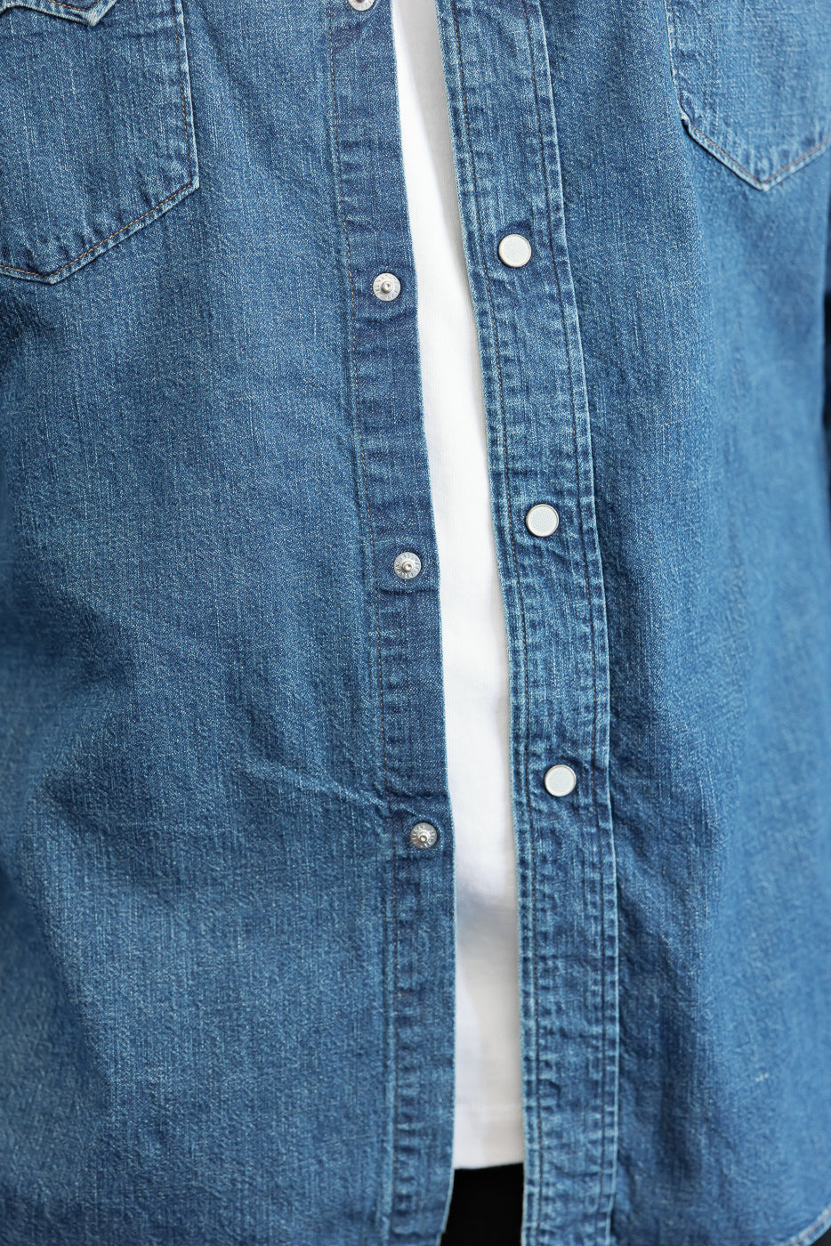 Close-up front view of a blue denim shirt showing button details and fabric texture.