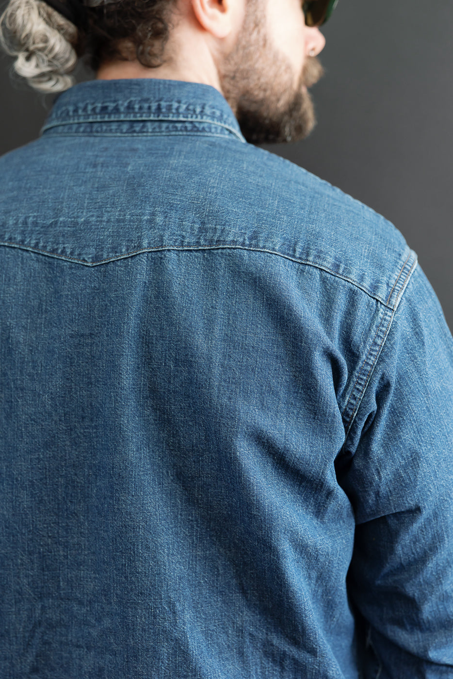 Back view close-up of a blue denim shirt on a 5'9
