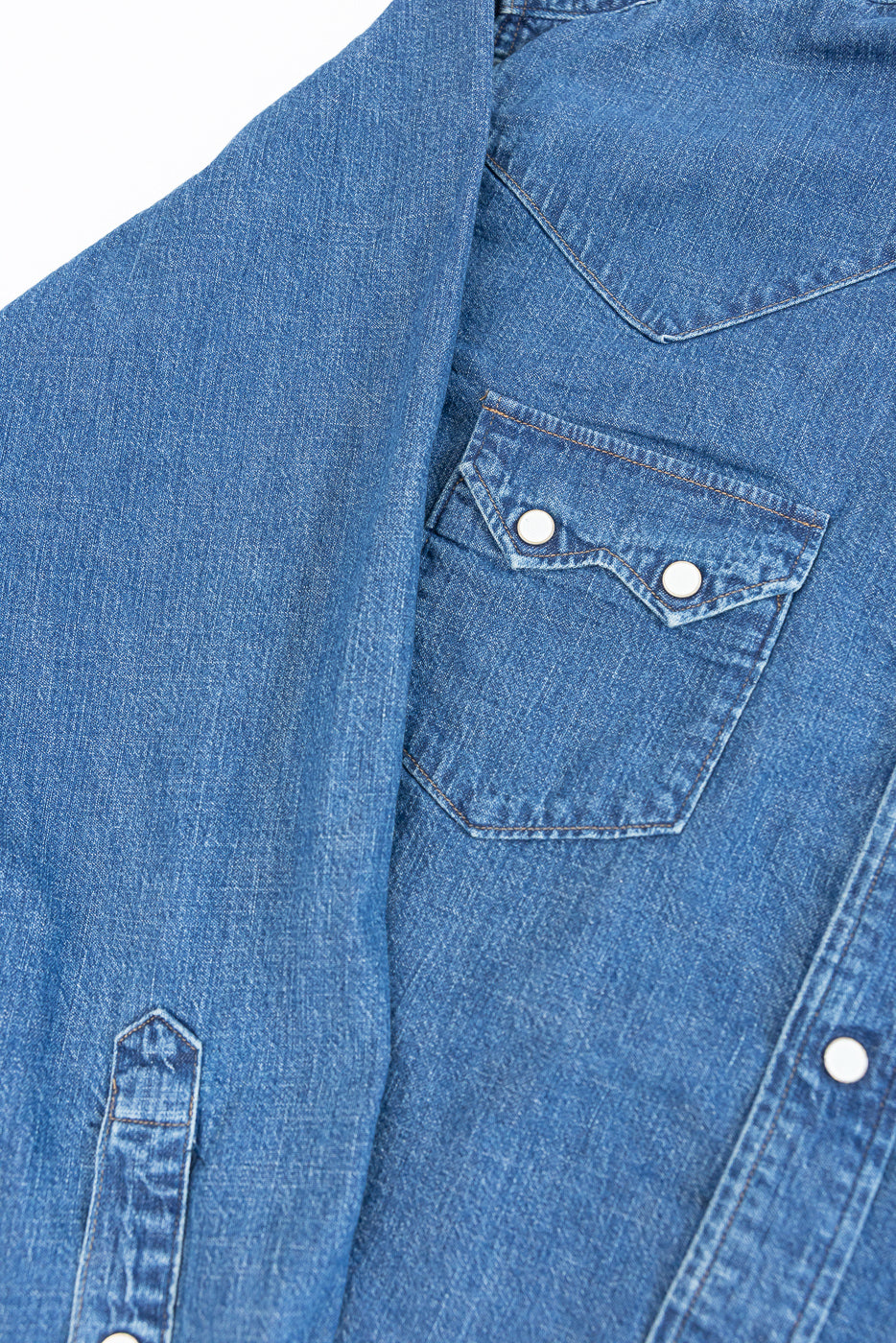 Close-up front view of a blue denim shirt showing pocket detail and fabric texture.
