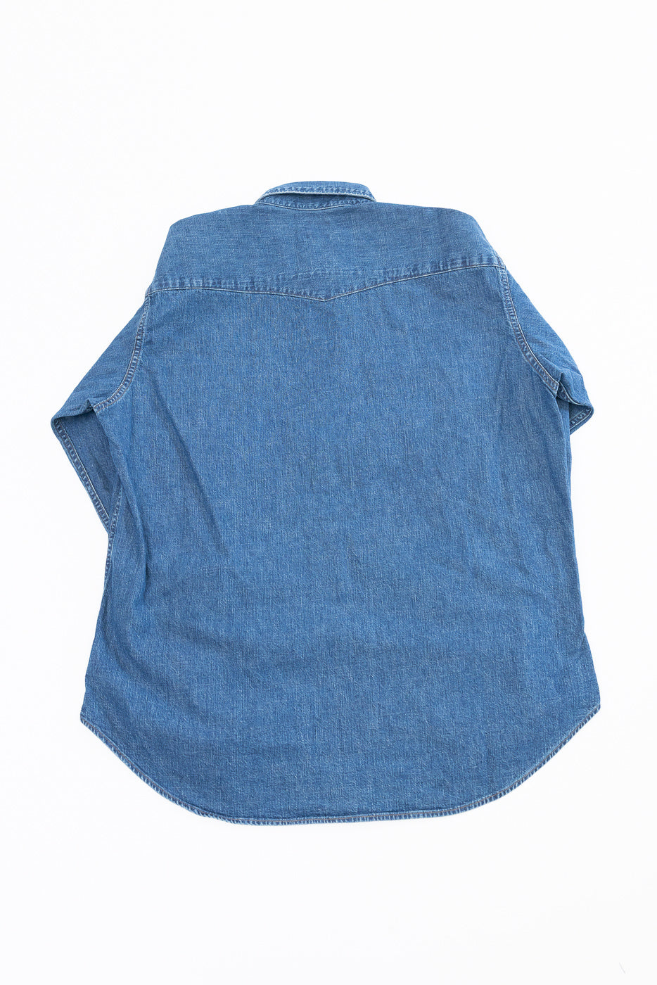 Back view flat lay of a blue denim long-sleeve shirt showing yoke and hem details.