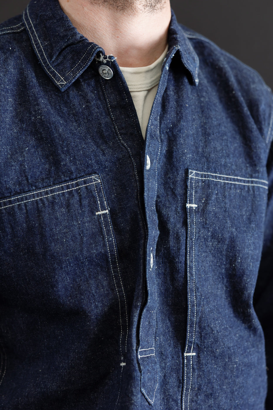 Close-up front view of a dark indigo denim shirt on a 5'9