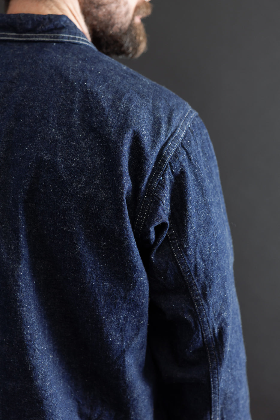 Close-up back view of a dark blue denim shirt showing fabric texture and shoulder seam.