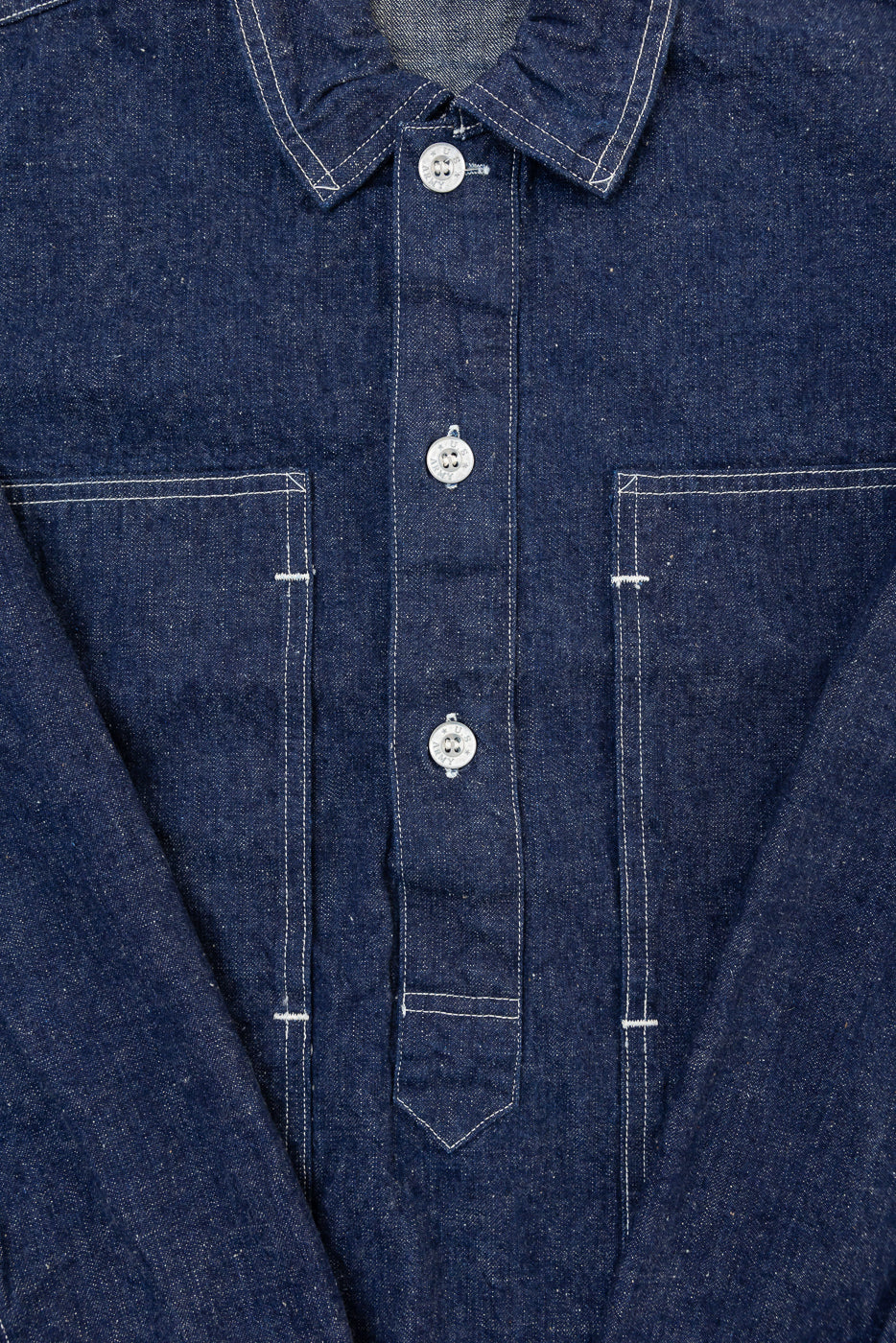 Close-up front view of a navy denim shirt showing the button placket, collar, and chest pockets.