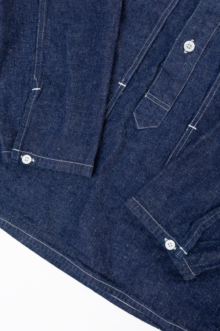 Close-up of the front of a navy blue denim shirt showing fabric texture, buttons, and stitching.