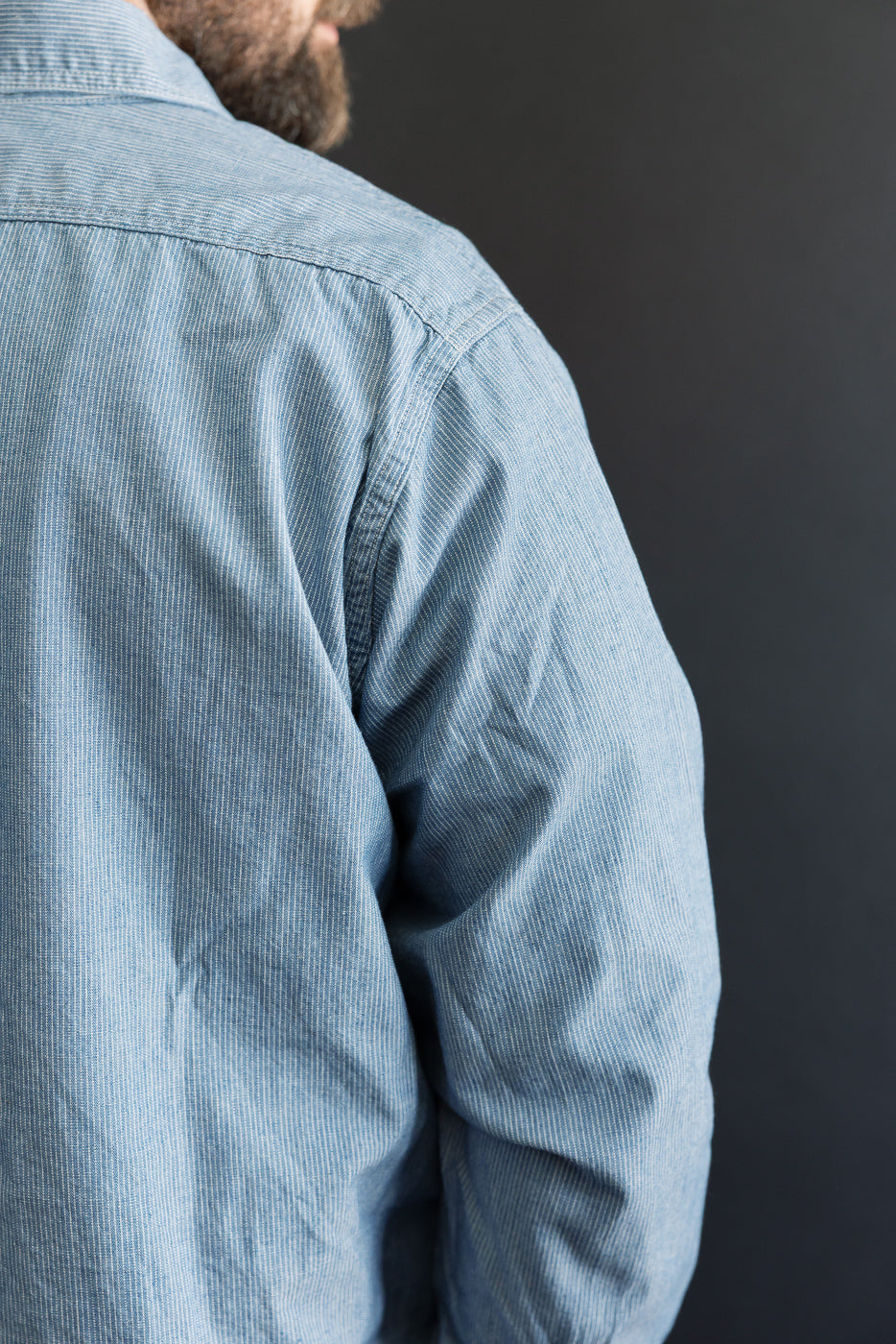The back view of the orSlow 01-8270-181k Relaxed Fit Chambray Work Shirt in Hickory, showcasing its fine pinstriped pattern and craftsmanship, with visible shoulder seam and part of the arm.