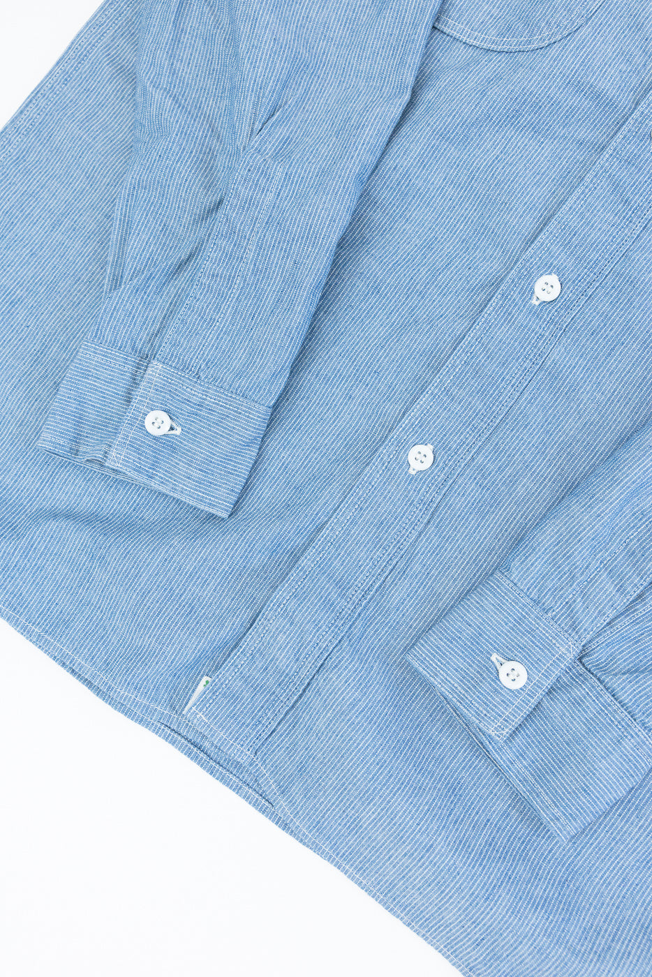01-8270-181k - Relaxed Fit Chambray Work Shirt - Hickory, features a light-blue pin-striped design, white buttons, a dagger collar, two button-flap chest pockets, and adjustable cuffs, embodying classic American workwear style.